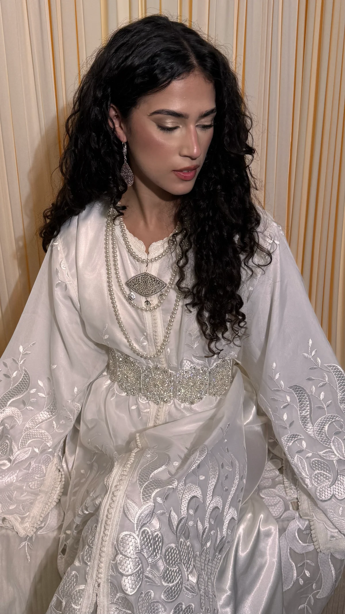 Mariée en caftan blanc brodé, parée de bijoux royaux et de perles